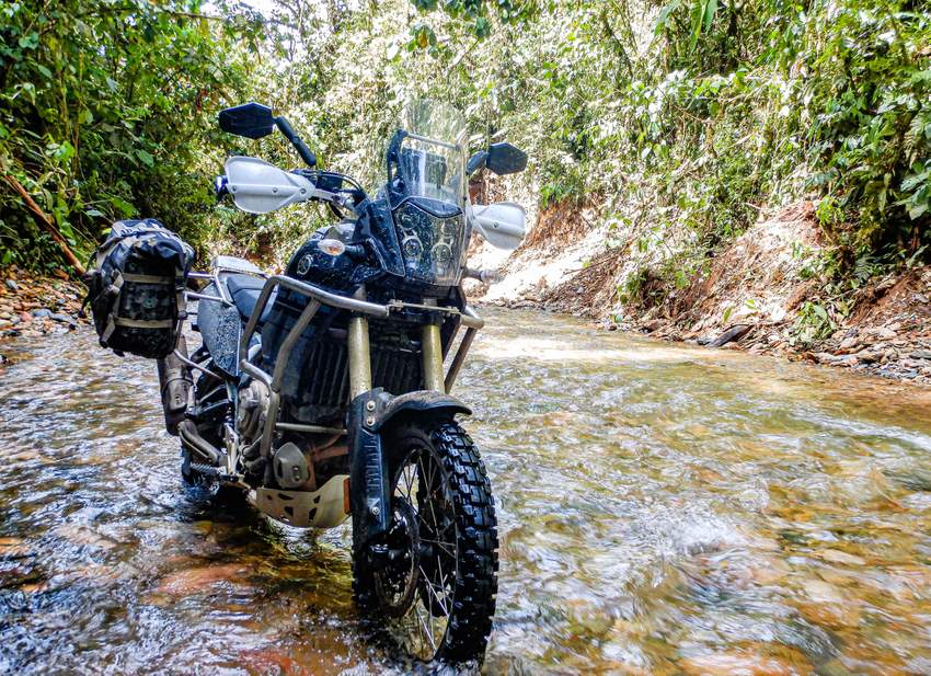 yamaha tenere riding up a shallow river in ecuador