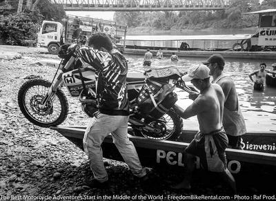 loading a dual sport motorcycle into a canoe in the amazon basin of ecuador