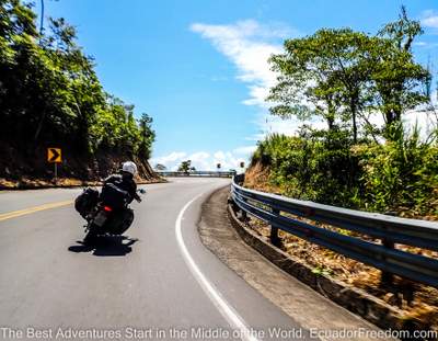 couple riding two up on a motorcycle on road going into the Ecuador Amazon basin